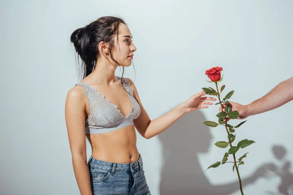 Corte vista de homem apresentando vermelho subiu para bela menina em roupa interior e jean — Fotografia de Stock