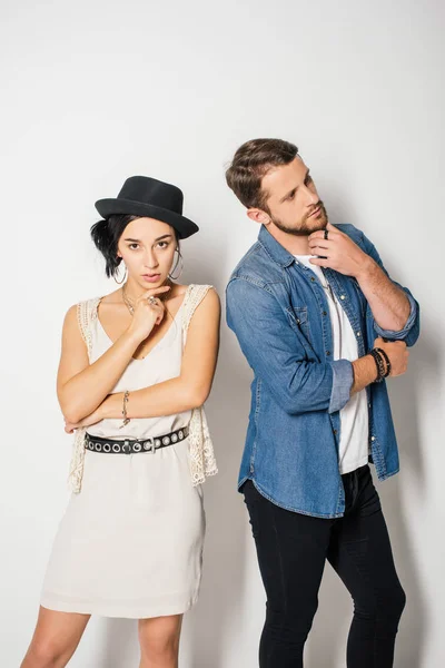 Handsome man looking away and beautiful girl in fashionable clothes looking at camera while posing — Stock Photo