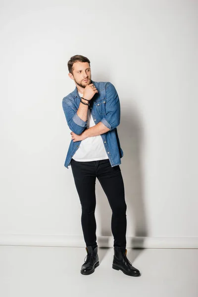 Full length view of young man in stylish clothes posing and looking away — Stock Photo