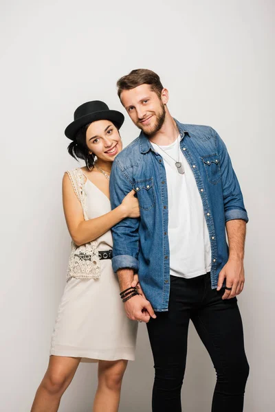 Jovem casal em roupas elegantes abraçando, sorrindo e olhando para a câmera — Fotografia de Stock