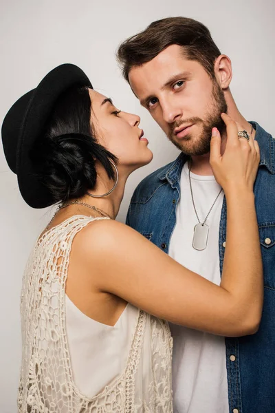 Handsome man in stylish clothes looking at camera while beautiful girl trying to kiss boyfriend — Stock Photo