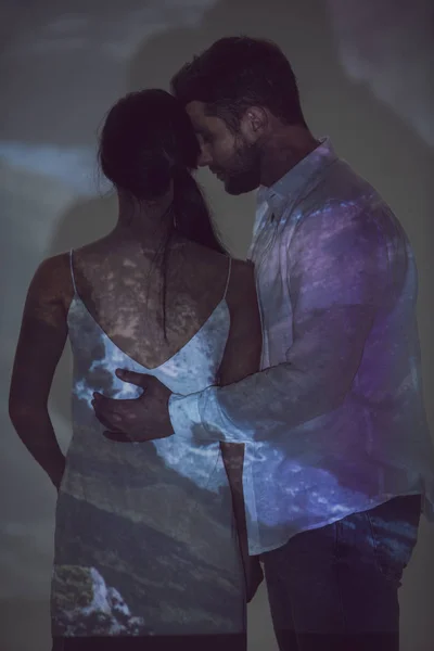 Young man hugging girlfriend while standing in dark place — Stock Photo