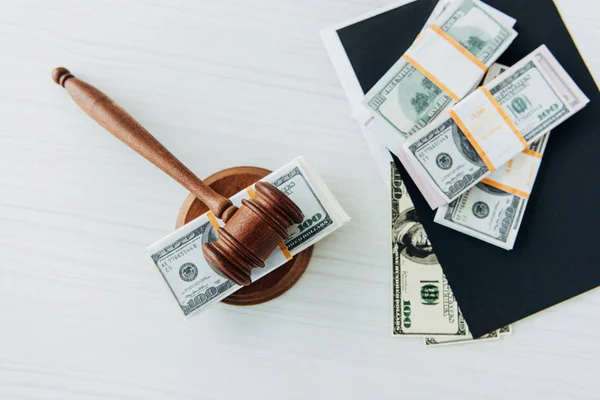 Top view of dollar banknotes near judge gavel and folder on table — Stock Photo
