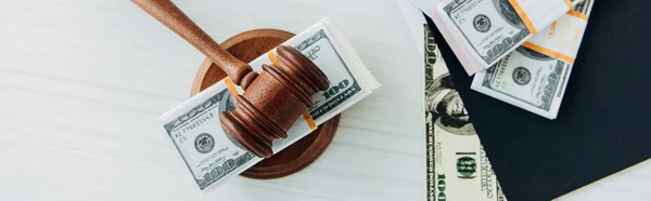 Panoramic shot of dollar banknotes near judge gavel and folder on table — Stock Photo