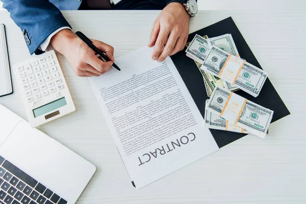 Вид зверху бізнесмен тримає ручку біля контракту і грошей в офісі — стокове фото