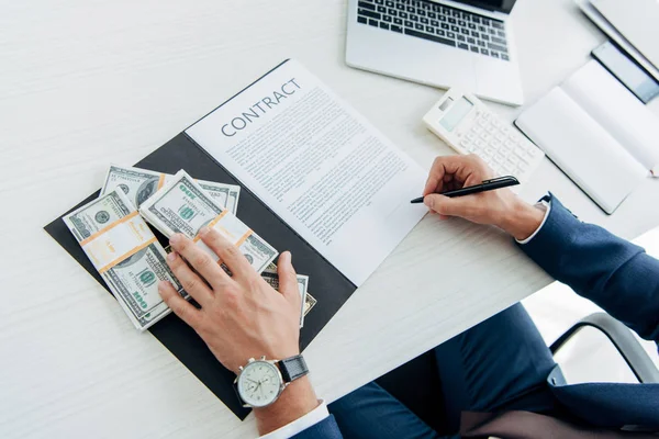 Vista cortada de homem segurando caneta perto de contrato e notas de dólar — Fotografia de Stock