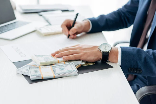 Cropped view of man touching bribe while signing contract — Stock Photo