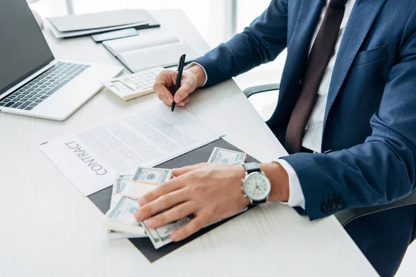 Cropped view of businessman touching bribe while signing contract — Stock Photo