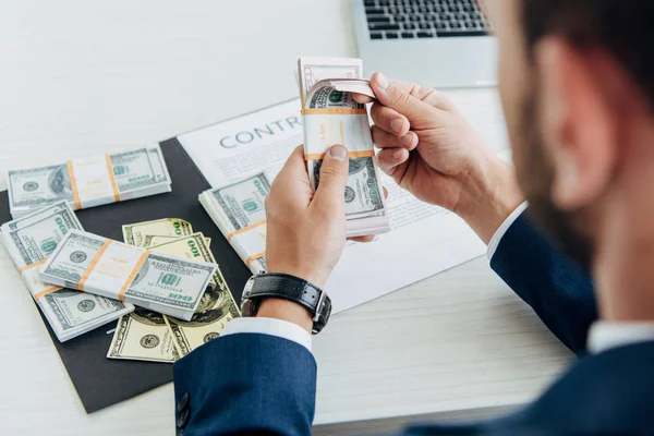 Enfoque selectivo de los hombres de negocios que tienen billetes en dólares cerca del contrato en el cargo - foto de stock