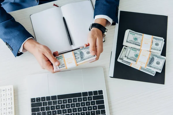 Top view of businessman holding bribe near laptop in office — Stock Photo