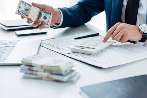 Selektiver Fokus des Geschäftsmannes mit Taschenrechner und das Halten von Geld in Vertragsnähe — Stockfoto