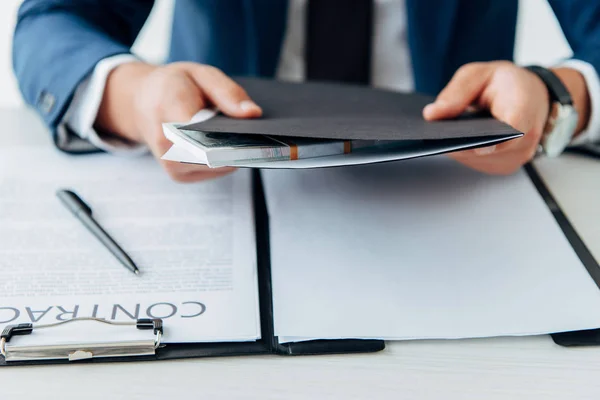 Selektiver Fokus des Mannes, der Ordner mit Geld in der Nähe des Vertrages mit Stift hält — Stockfoto