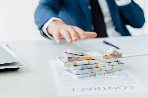 Enfoque selectivo del hombre de negocios gesticulando cerca de dinero y contrato en la mesa - foto de stock