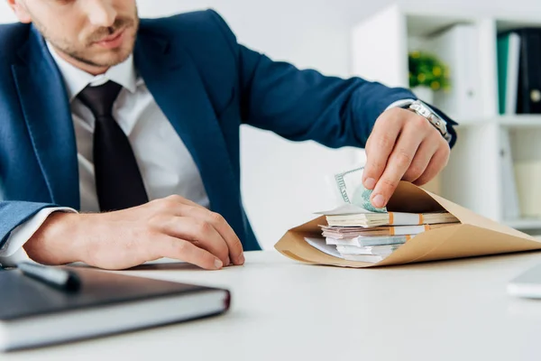 Selective focus of businessman touching money in envelope on table — Stock Photo