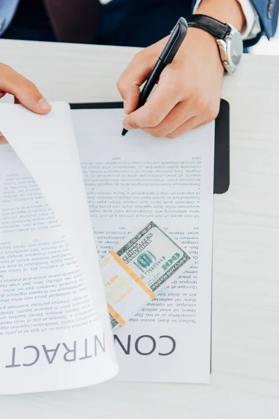 Top view of businessman holding pen while signing contract near money on table — Stock Photo