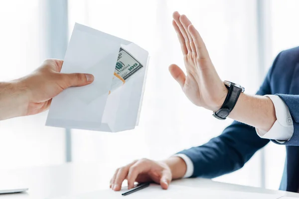 Cropped view of man gesturing near business partner giving envelope with money in office — Stock Photo