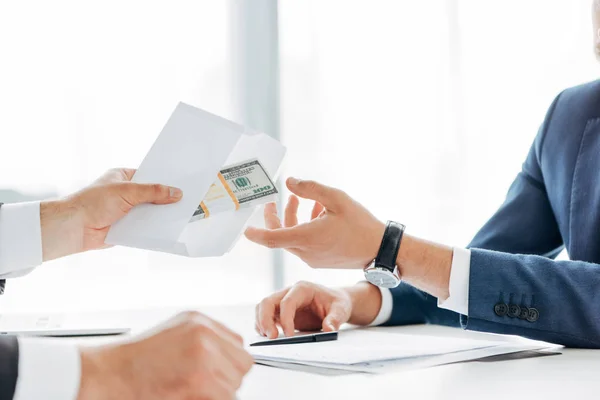 Visão cortada do homem dando envelope com dinheiro para parceiro de negócios — Fotografia de Stock