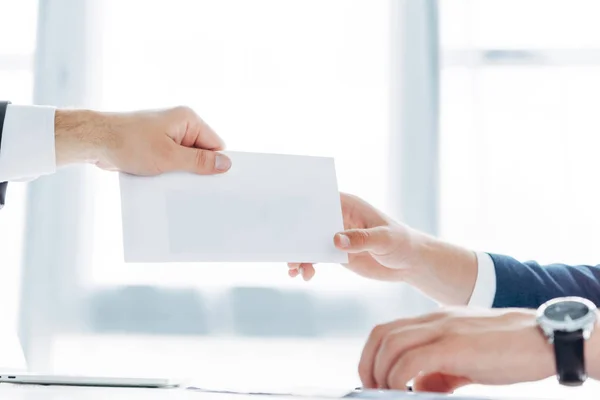 Visão cortada de empresário dando envelope branco com suborno ao parceiro de negócios — Fotografia de Stock