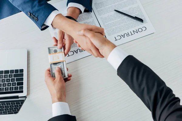 Top view of man giving bribe and shaking hands with business partner — стоковое фото