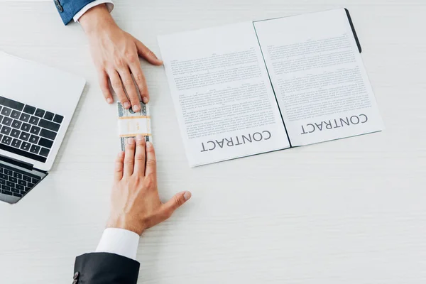 Top view of business partners touching money near contract on table — Stock Photo