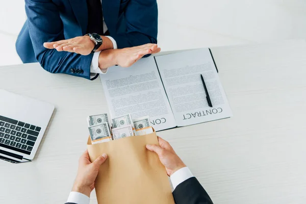 Top view of man gesturing near business partner giving envelope with bribe — Stock Photo