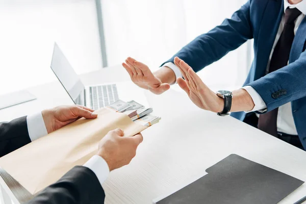 Cropped view of man gesturing near business partner giving envelope with bribe — Stock Photo