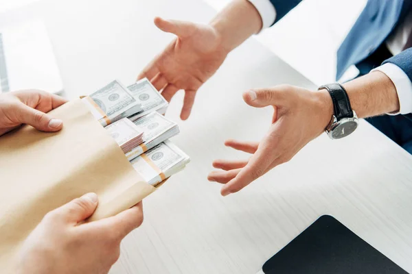 Cropped view of man taking envelope with cash near business partner — Stock Photo
