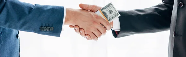 Panoramic shot of man giving bribe to business partner and shaking hands isolated on white — Stock Photo