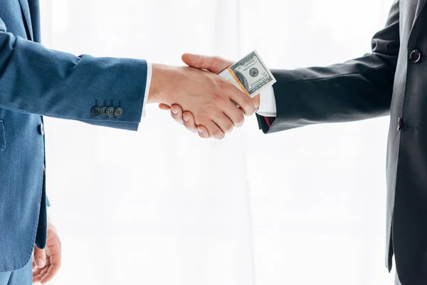 Cropped view of man giving bribe to business partner and shaking hands on white — Stock Photo