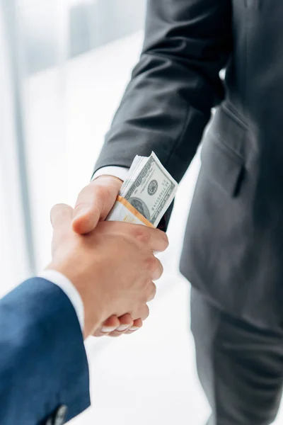 Cropped view of man giving bribe to business partner and shaking hands in office — Stock Photo