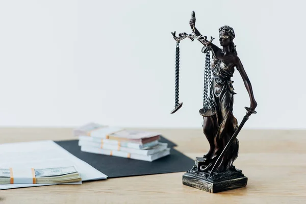 Selective focus of dollar banknotes on folder near statuette of justice — Stock Photo