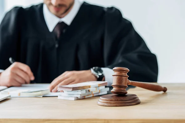 Selective focus of wooden gavel near judge writing in office — Stock Photo