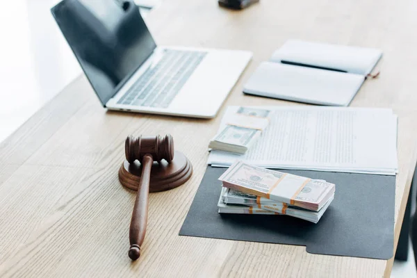 Selective focus of wooden gavel near money and laptop in office — Stock Photo
