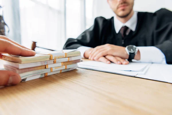 Cropped view of judge sitting near man giving bribe — Stock Photo