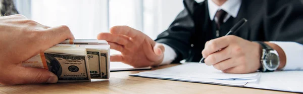 Panoramic shot of man giving cash to judge in office — Stock Photo