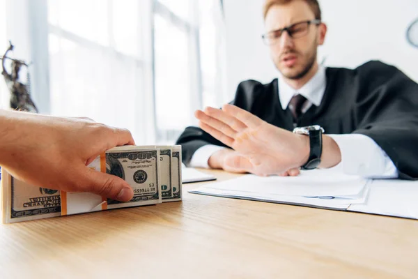 Selective focus of man holding cash near judge gesturing in office — Stock Photo