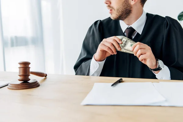 Cropped view of judge holding dollar banknotes near gavel, documents and pen — Stock Photo