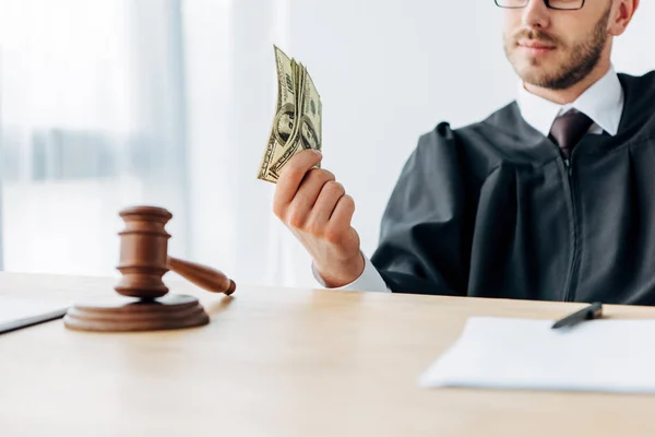 Selective focus of gavel near judge holding dollar banknotes — Stock Photo