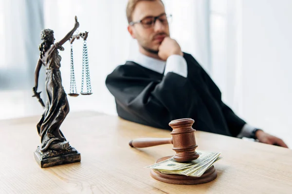 Selektiver Fokus von Hammer und Justizstatuette nahe Richter beim Betrachten von Dollarnoten — Stockfoto