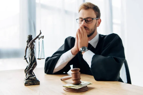 Selective focus of wooden gavel with money near judge in glasses covering face — Stock Photo