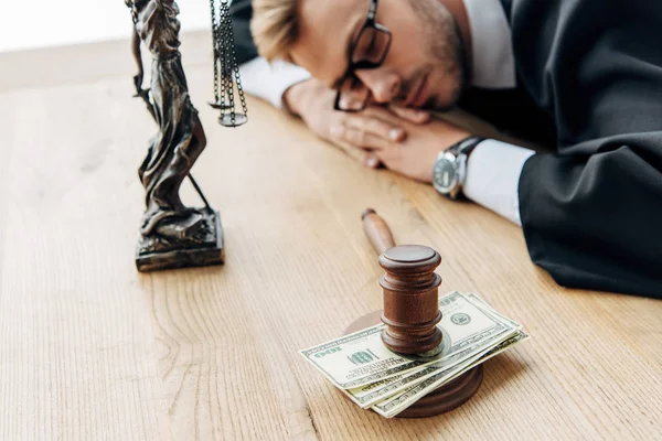 Selective focus of tired judge in glasses sleeping on table near gavel and money — Stock Photo