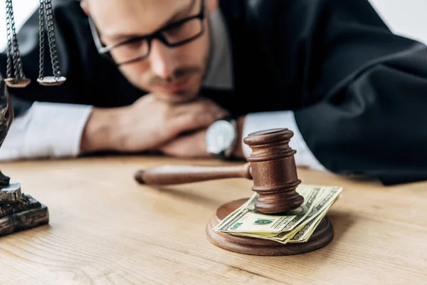 Selective focus of wooden gavel on money near judge in glasses — Stock Photo