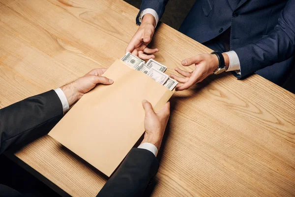 Top view man giving envelope with bribe to judge near wooden table — Stock Photo
