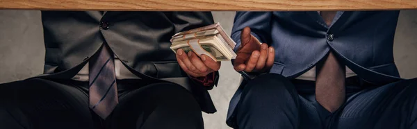Tiro panorâmico de homem dando suborno ao parceiro de negócios enquanto sentado na cadeira — Fotografia de Stock