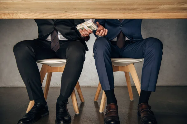 Ponto de vista cortado homem dando suborno ao parceiro de negócios enquanto sentado na cadeira — Fotografia de Stock