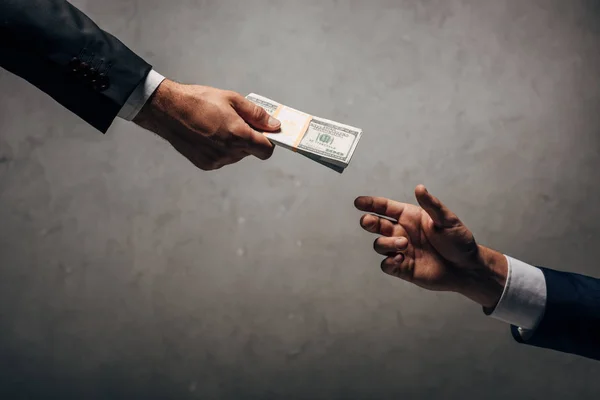 Cropped view man giving bribe to business partner on grey — Stock Photo