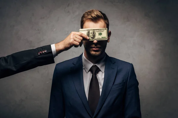Cropped view of man covering face of judge with money on black — Stock Photo