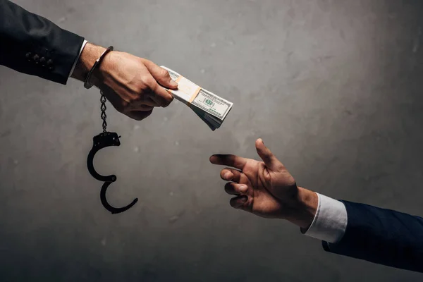 Cropped view man in handcuffs giving bribe to business partner on grey — Stock Photo