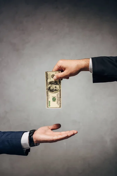 Cropped view man taking bribe near business partner on grey — Stock Photo