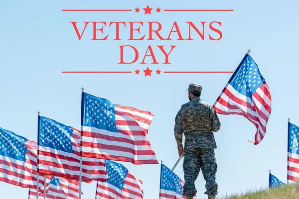 Man in military uniform and cap standing and holding american flag with veterans day illustration — Stock Photo